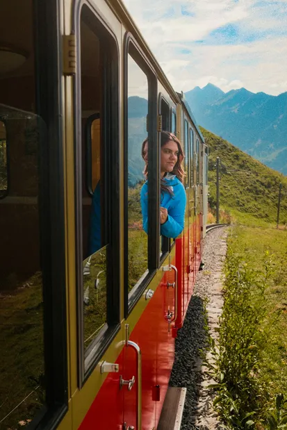 Een reiziger geniet van een ongebruikelijk vervoermiddel: het uitzicht vanuit een treinraam in de Zwitserse Alpen.